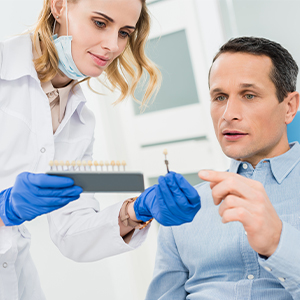 Dentist explaining dental implant treatment to a patient during a consultation