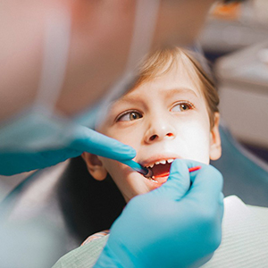 Dental hygienist cleaning a young patient’s teeth during a routine oral hygiene appointment.